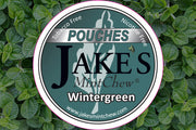 Jake's Mint Chew Wintergreen Pouches product label against a background of fresh mint leaves, promoting a tobacco-free and nicotine-free wintergreen-flavored alternative